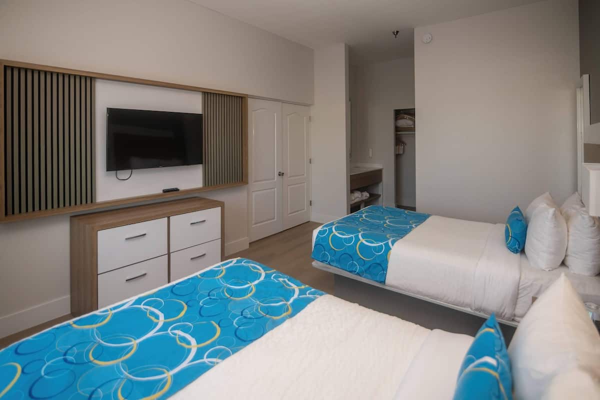 A hotel room with two beds, a TV, a wardrobe, and a bathroom.
