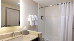 A bathroom with a sink, mirror, towel rack, and shower curtain.