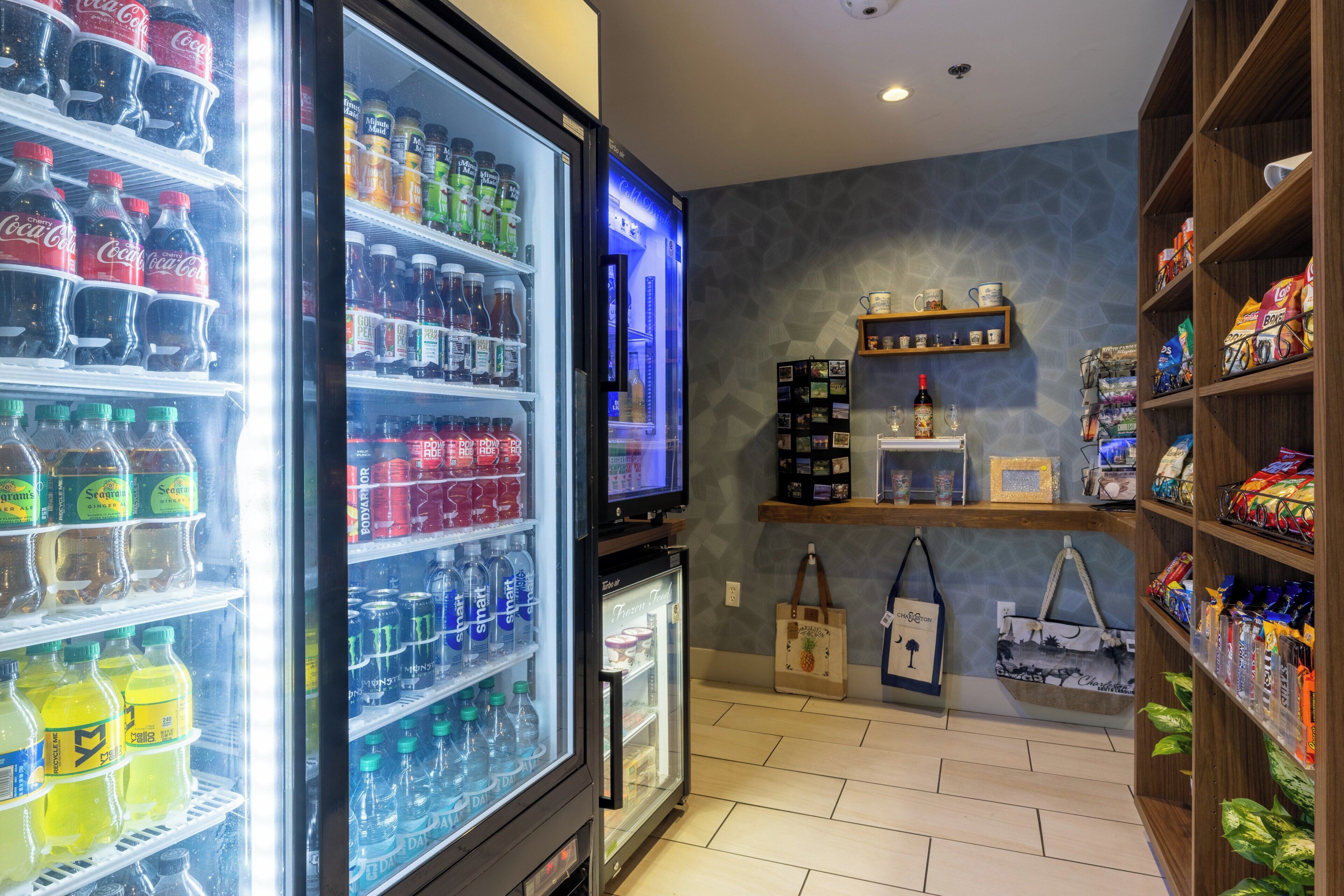 A beverage refrigerator stocked with various drinks, a television, and shelves with snacks and small items.