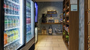 Un magasin dont les étagères sont remplies de boissons, où l’on expose des tasses, et où un panneau indique la section dédiée aux produits alimentaires.