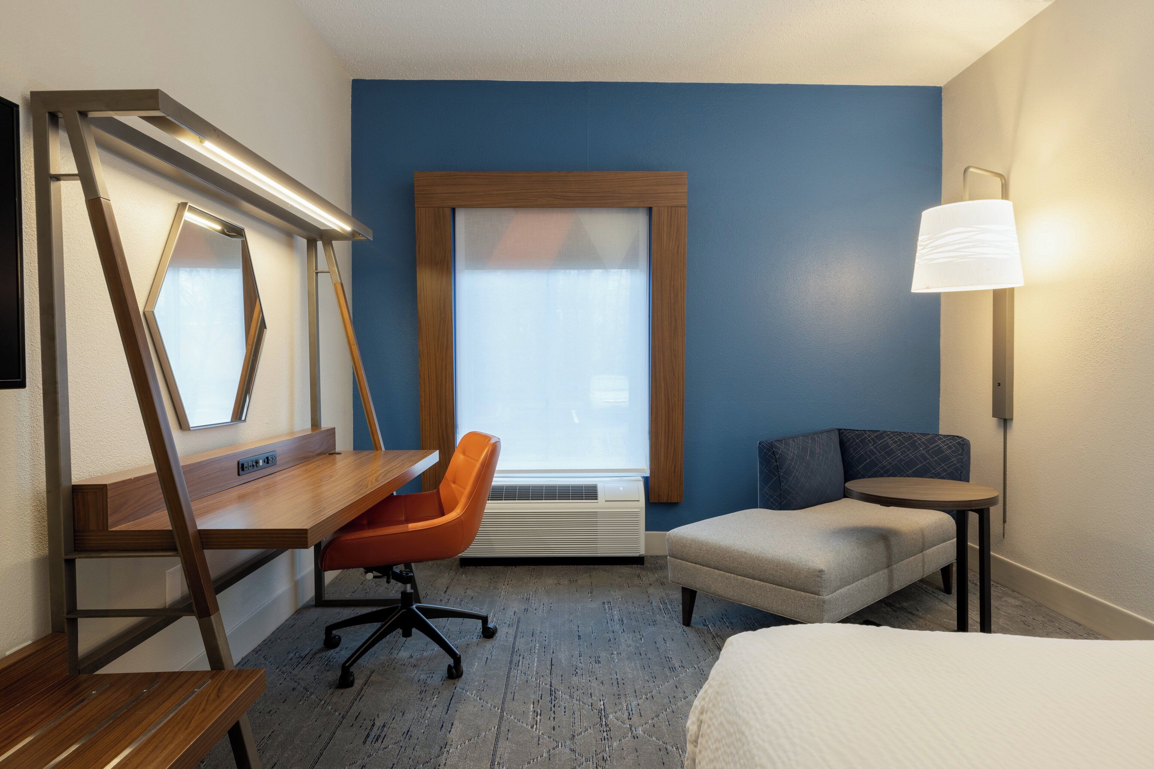 A hotel room with a desk, chair, sofa, and bed.