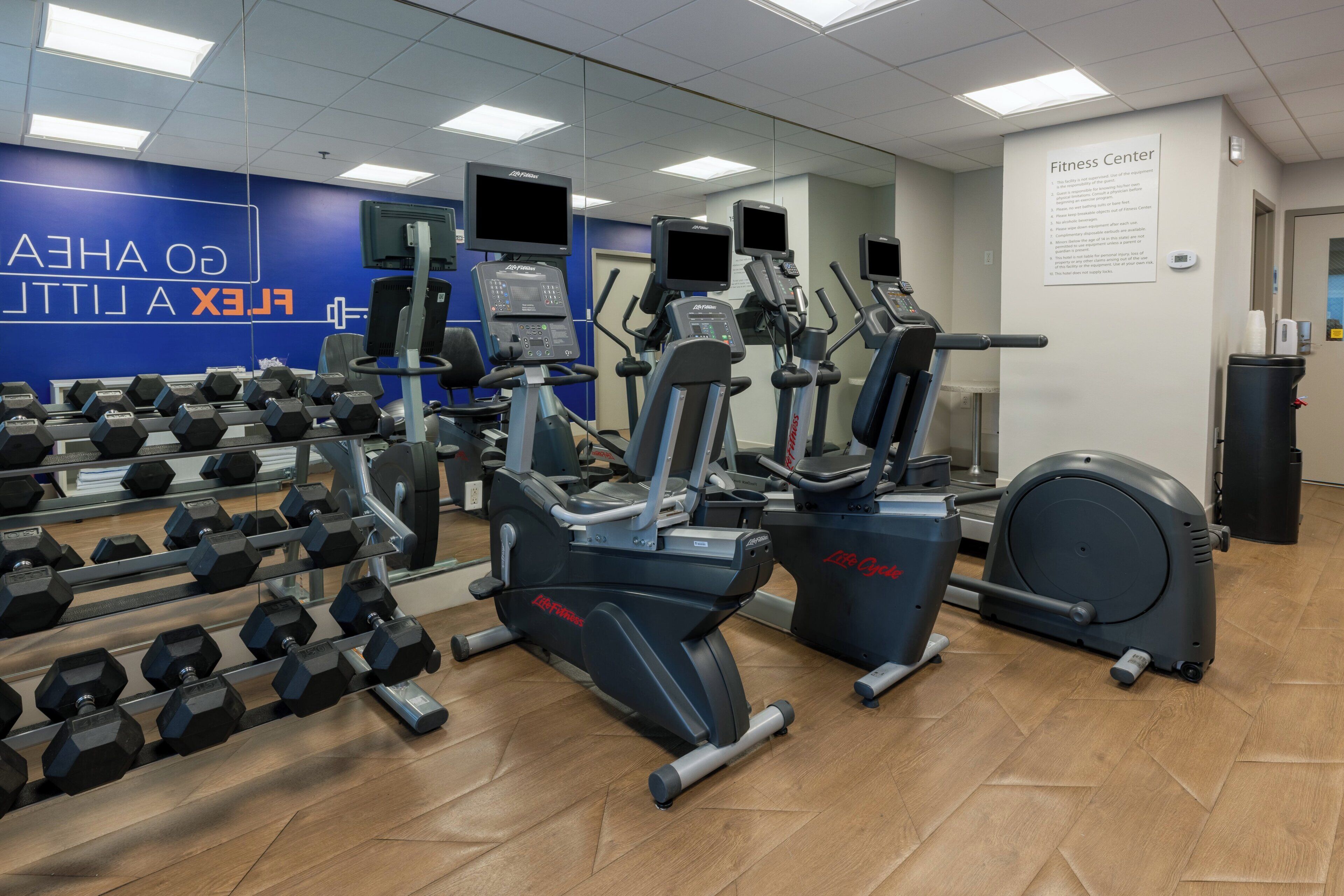 A gym with exercise equipment, a mirror, and a wall sign.