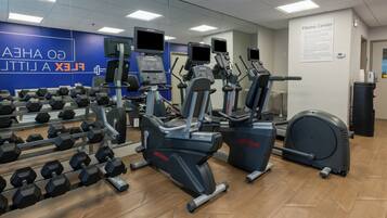 A gym with exercise equipment, a mirror, and a wall sign.