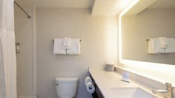 A bathroom with a toilet, a sink, a mirror, and a shower curtain.