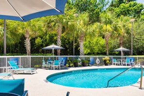 Una piscina al aire libre, sillones reclinables de piscina