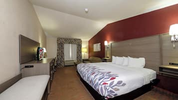 Una camera d'albergo con un letto, una scrivania, una televisione e una finestra con tende.