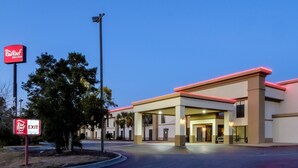 A Red Roof Inn & Suites with a clear sky, an exit sign, and a well-lit entrance. - Red Roof Inn Yemassee (Yemassee)