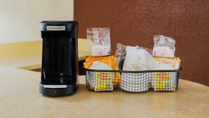 A coffee maker and a basket of packaged food items on a countertop. - Red Roof Inn Yemassee (Yemassee)