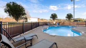 A circular swimming pool with a surrounding deck, equipped with lounge chairs and a fence. - Red Roof Inn Yemassee (Yemassee)