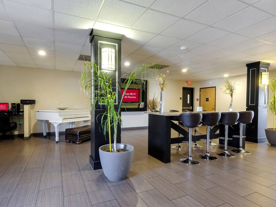 Un espace d’accueil comprenant un piano, un bureau et plusieurs tabourets de bar.