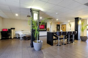 A reception area with a piano, a desk, and multiple bar stools.