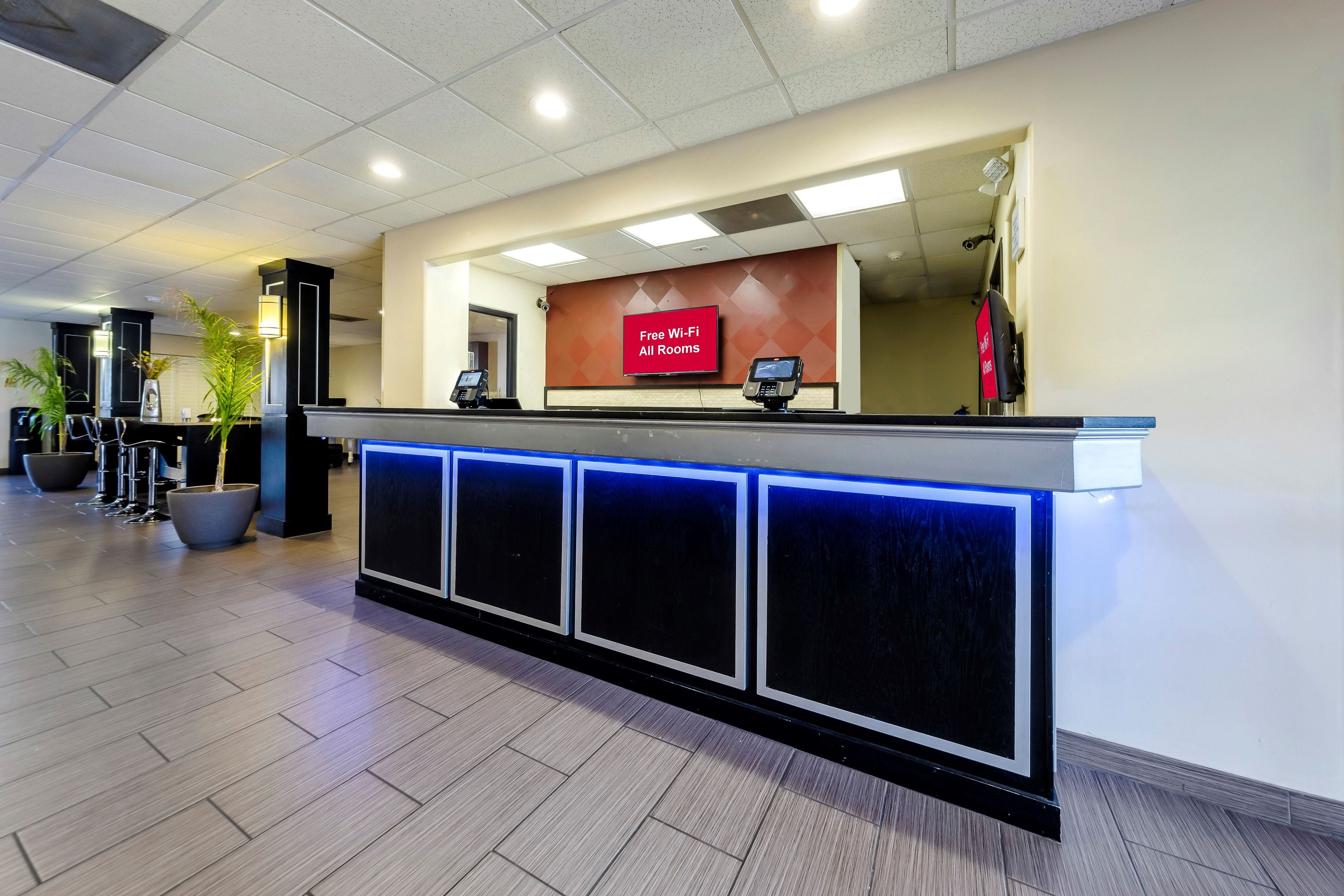 En hotellreception med en digital skärm, en skylt som visar att det finns kostnadsfritt Wi-Fi och en övervakningskamera.