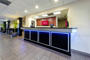 Una recepción de hotel con una pantalla digital, un letrero que indica Wi-Fi gratuito y una cámara de seguridad.