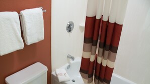 A bathroom with a toilet, a bathtub, and a shower curtain. - Red Roof Inn Yemassee (Yemassee)