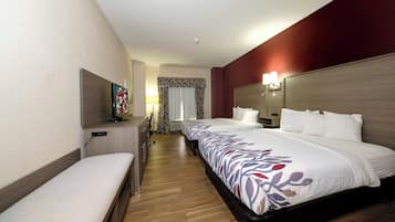 A hotel room with a bed, a desk, a TV, and a window with curtains.