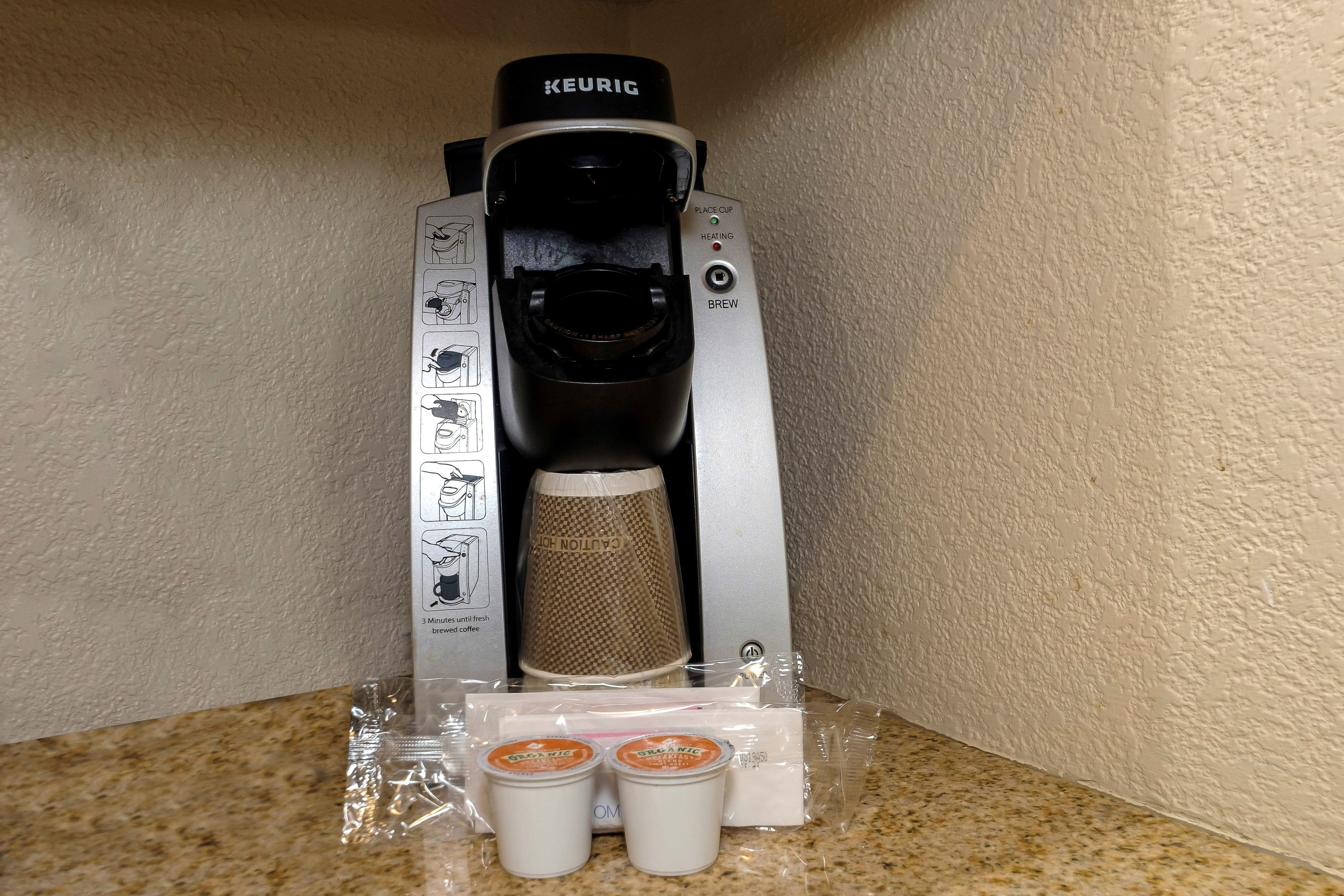Une machine à café Keurig dotée d’un support pour tasse, d’un compartiment pour dosettes de café et d’une dosette de café.