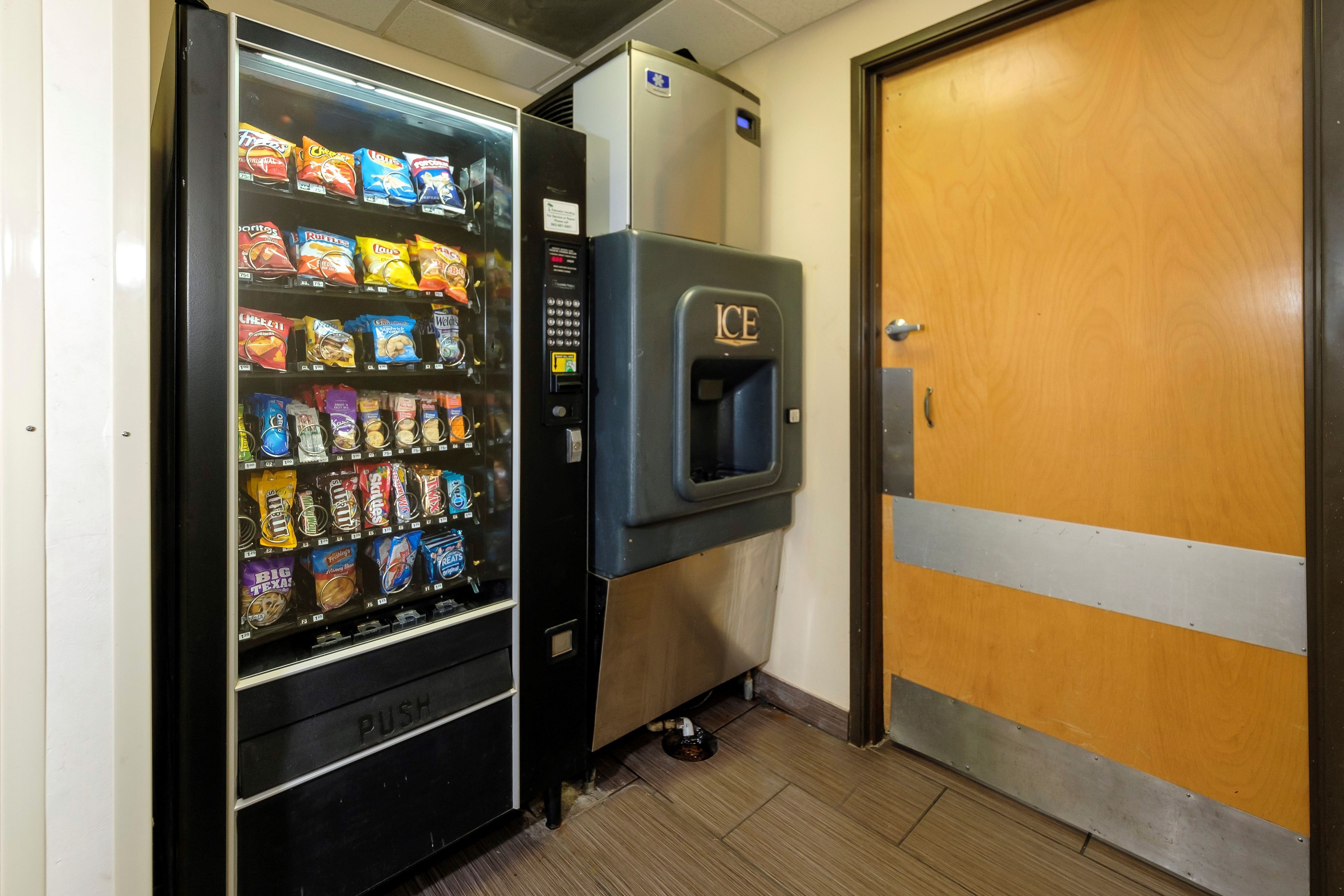 A vending machine with snacks and a water dispenser in a hallway.