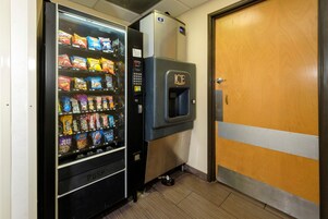 Máquina expendedora con aperitivos y dispensador de agua en un pasillo.