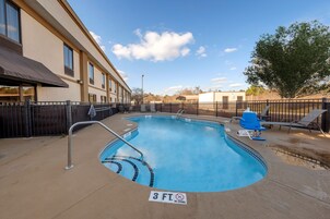 A swimming pool with a 3 FT depth marker, surrounded by lounge chairs and a fence.