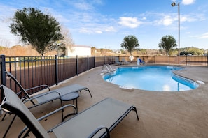 A circular swimming pool with a surrounding deck, equipped with lounge chairs and a fence. - Red Roof Inn Yemassee (Yemassee)