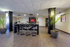 A modern lobby with a reception desk, bar stools, potted plants, and a flat-screen TV displaying 'Free Wi-Fi All Rooms'. - Red Roof Inn Yemassee (Yemassee)
