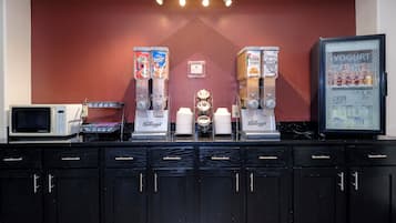 Un espace dédié aux boissons, équipé de plusieurs distributeurs, d’un four à micro-ondes et d’un réfrigérateur.