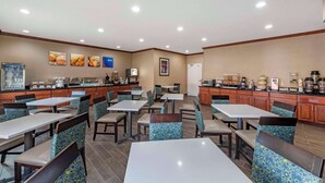 A restaurant with multiple tables and chairs, a kitchen area, and various food display items. - Comfort Inn & Suites Middletown - Franklin (Franklin)