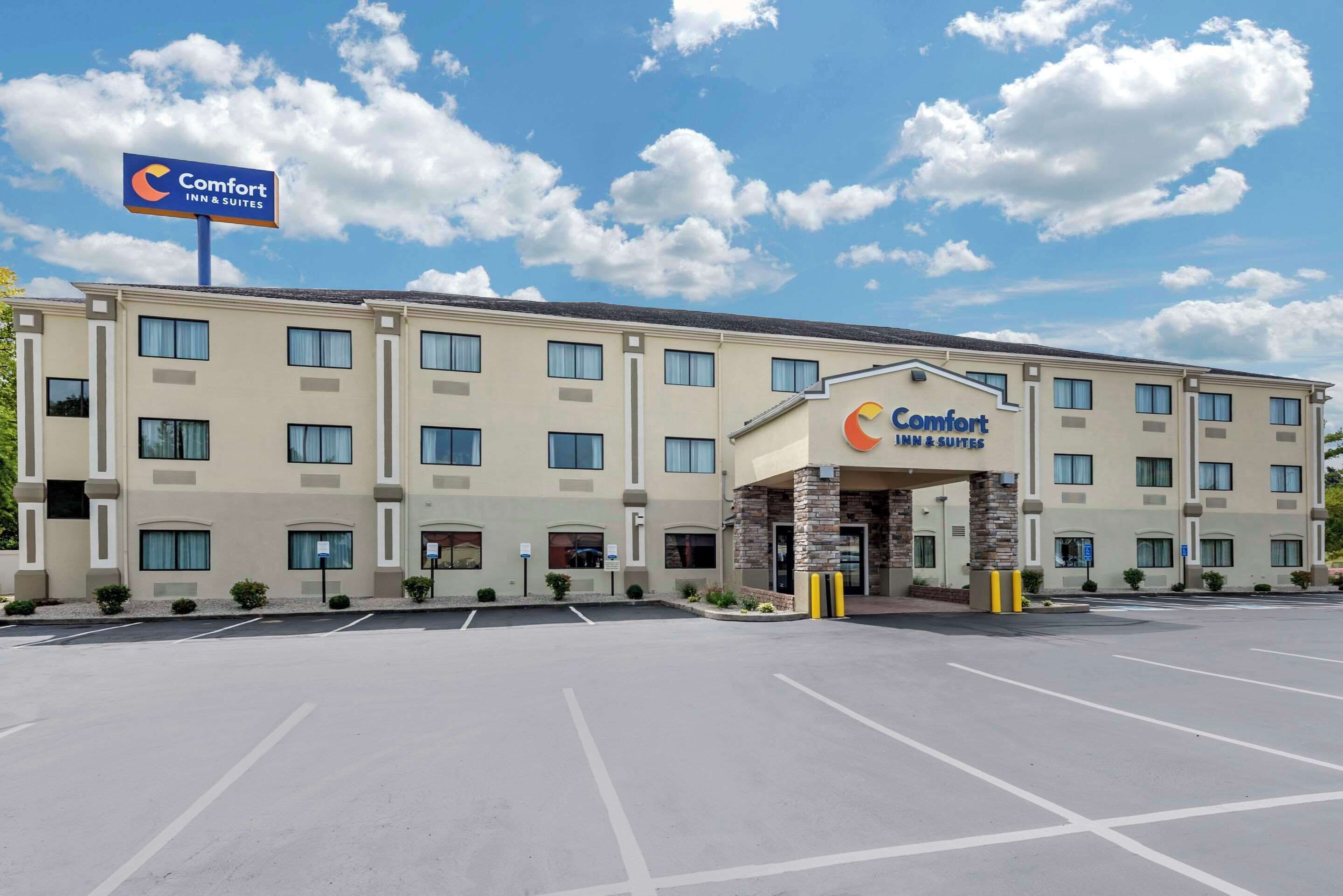 Un hotel Comfort Inn & Suites con un amplio estacionamiento y un cielo azul despejado.