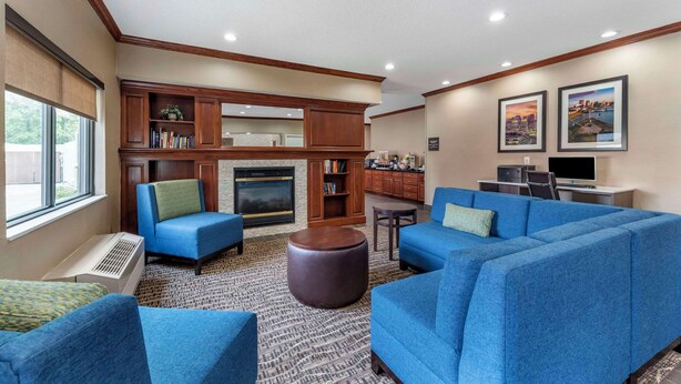A living room with blue sofas, a fireplace, a TV, and a bookshelf. - Comfort Inn & Suites Middletown - Franklin (Franklin)