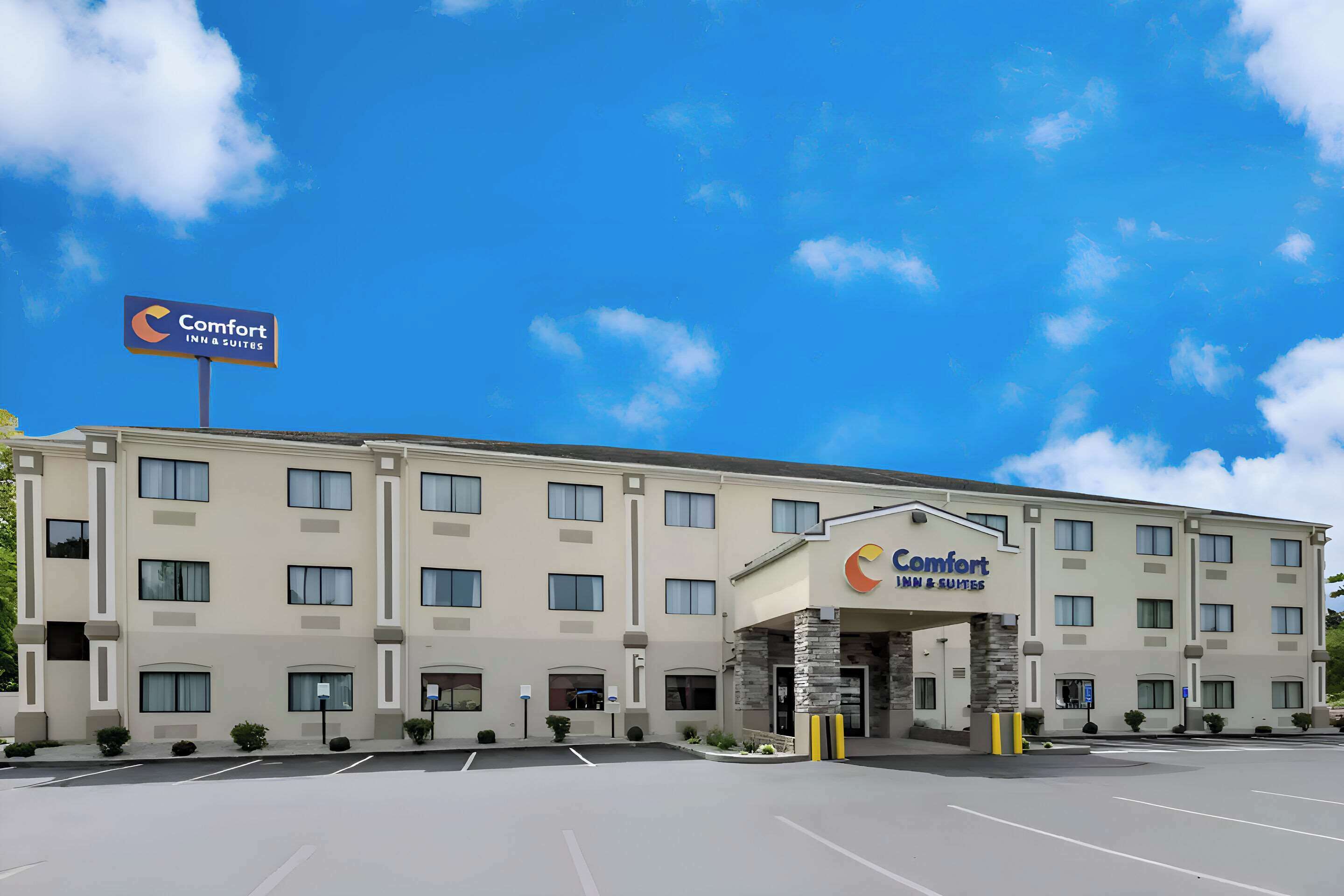 A Comfort Inn & Suites hotel with a modern facade, multiple windows, and a clear blue sky.