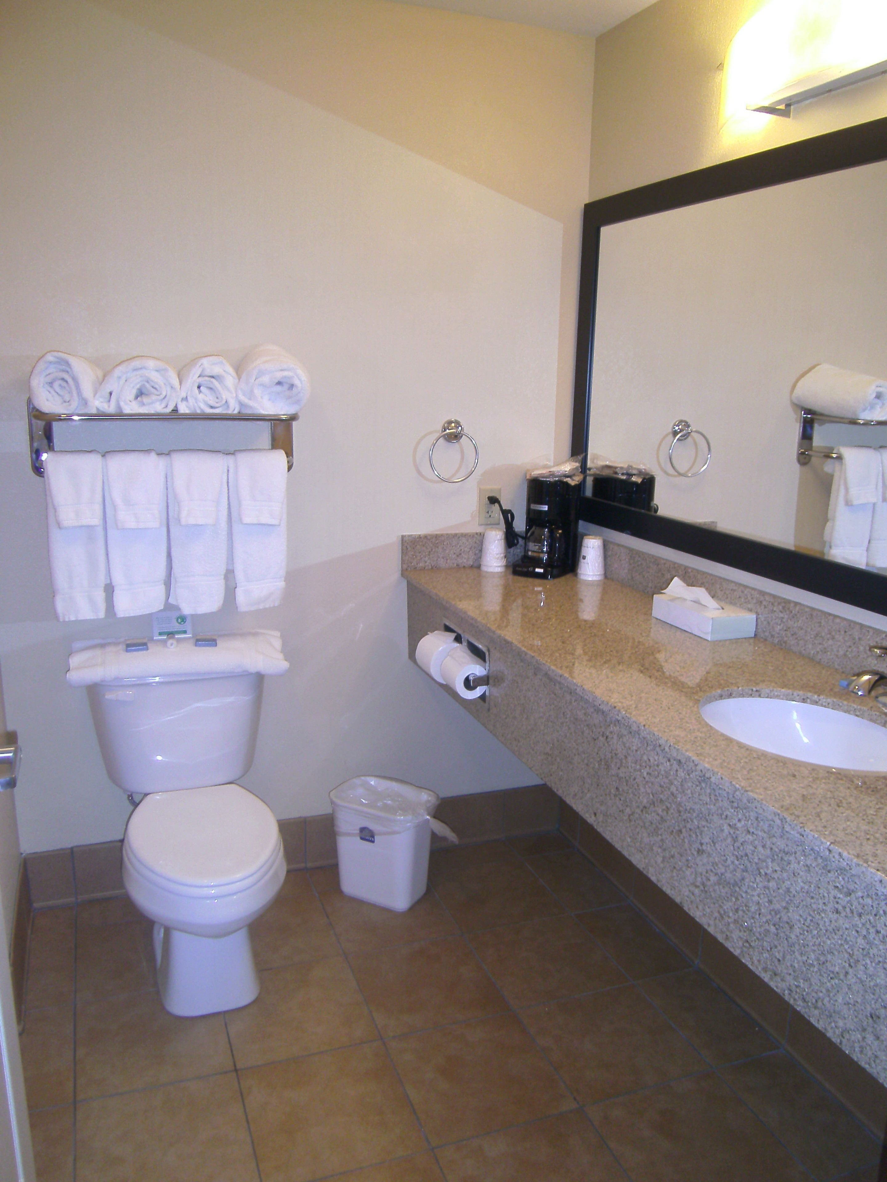 Un baño con inodoro, lavamanos y perchero para toallas.