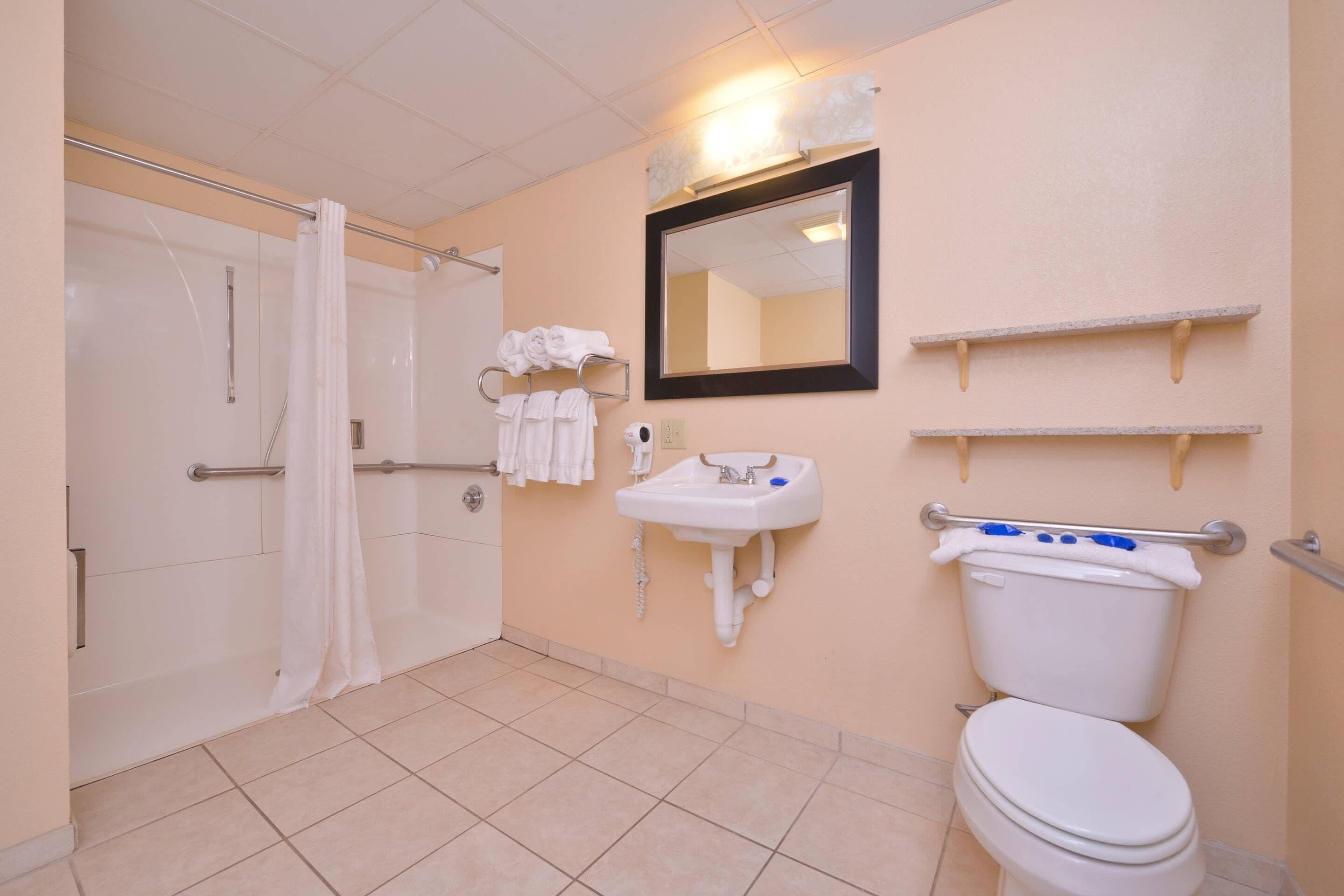 A bathroom with a shower, toilet, sink, and towel rack.