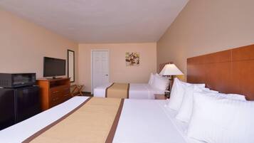 A hotel room with two beds, a TV, a microwave, a desk, and a lamp.