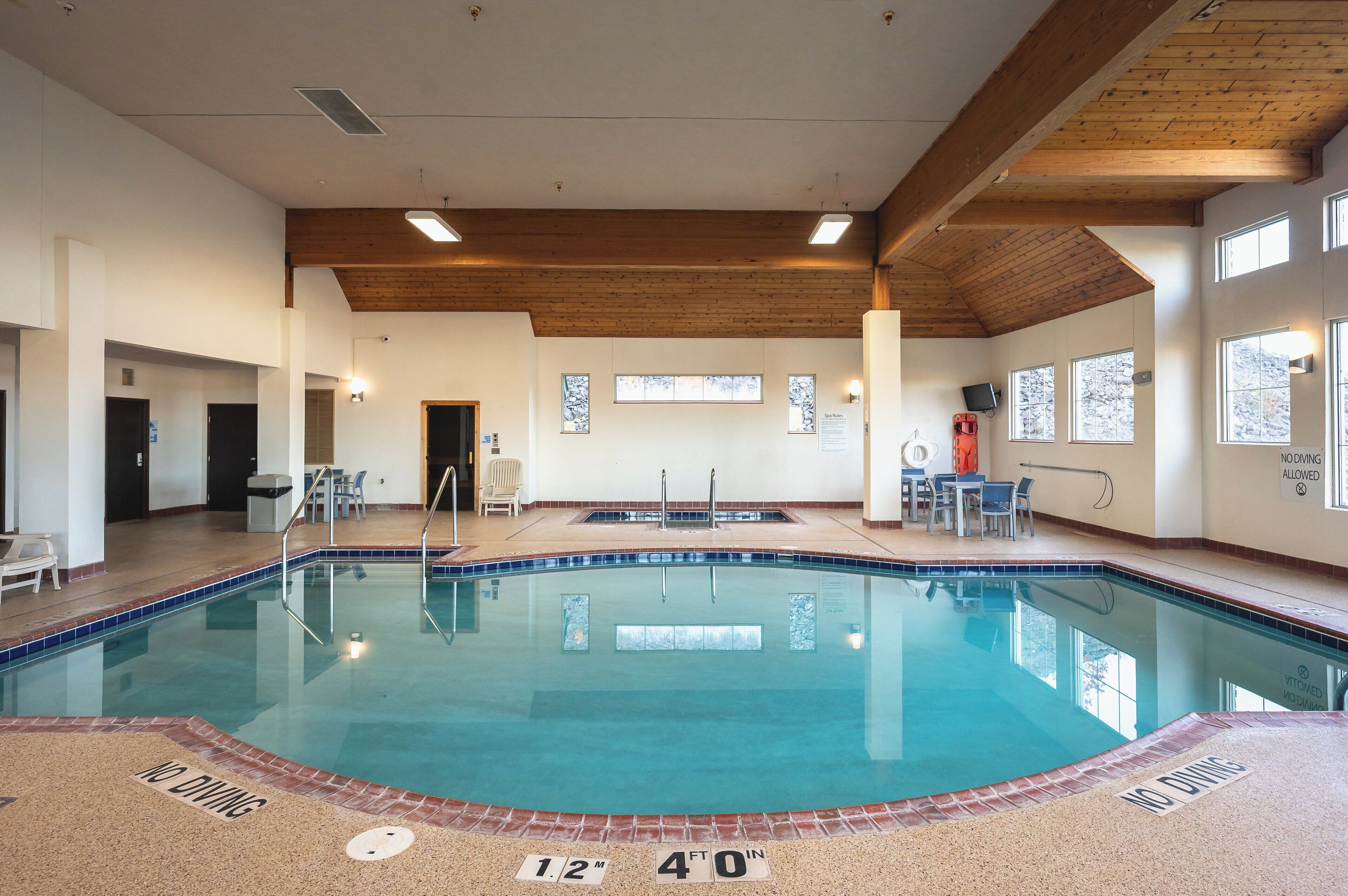 An indoor swimming pool with a wooden ceiling, clear poolside area, and a no diving sign.