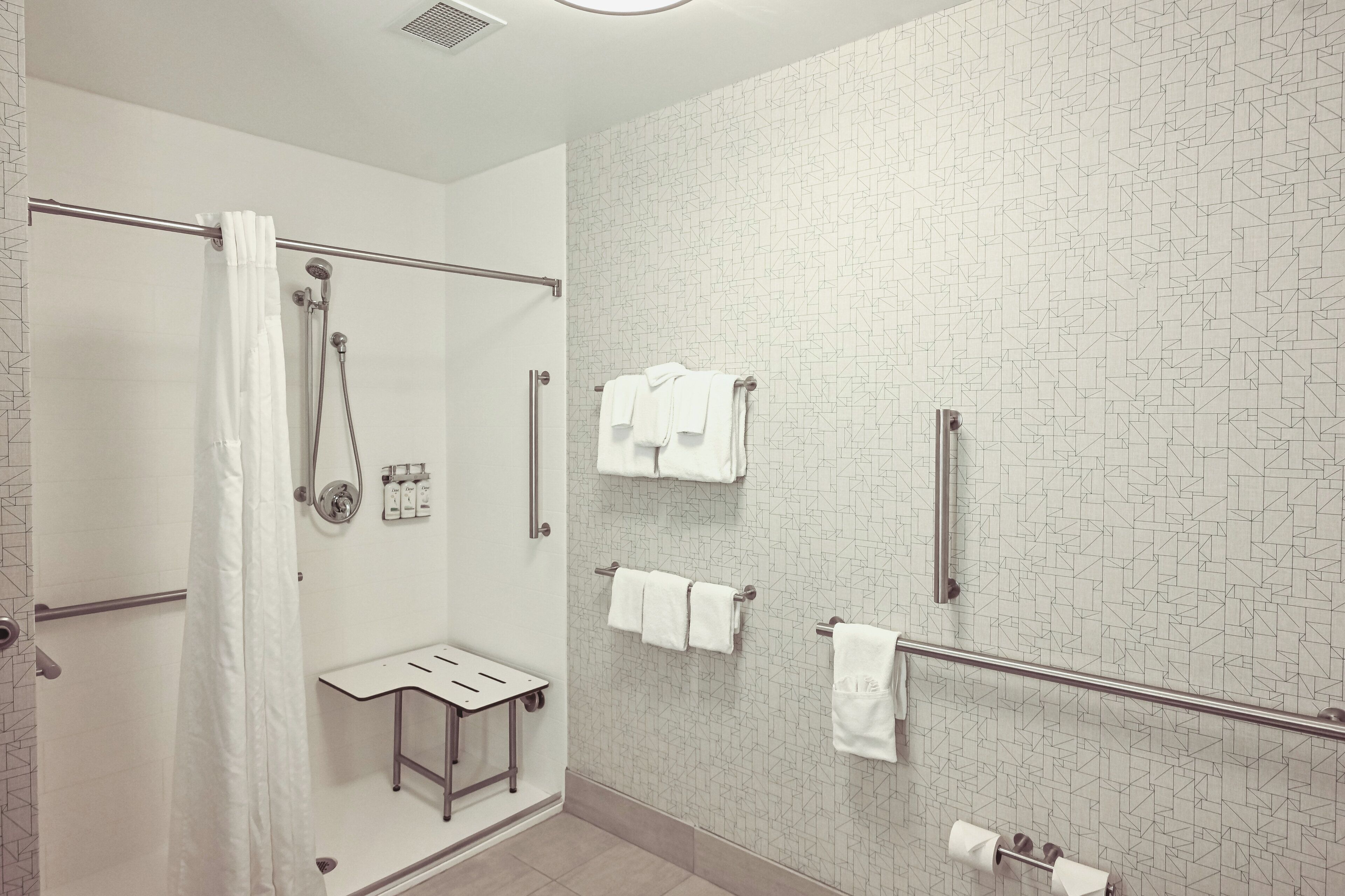 Une salle de bain moderne équipée d’une douche, d’un porte-serviettes et d’une petite table.
