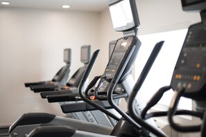 Varias bicicletas estáticas alineadas en un gimnasio, con pantallas digitales.