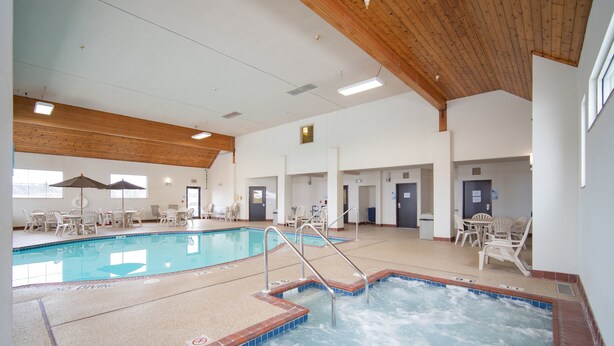 A swimming pool with a separate hot tub area, surrounded by lounge chairs and tables. - Holiday Inn Express Houghton-Keweenaw by IHG (Houghton)