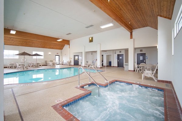A swimming pool with a separate hot tub area, surrounded by lounge chairs and tables. - Holiday Inn Express Houghton-Keweenaw by IHG (Houghton)