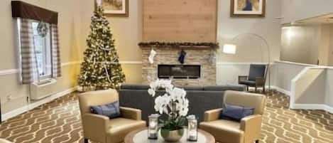 Un salón comedor amplio con chimenea, un árbol de Navidad y una moderna lámpara de araña.