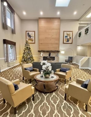 Un salón comedor amplio con chimenea, un árbol de Navidad y una moderna lámpara de araña.