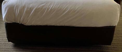 Una habitación de hotel con una cama grande, dos mesitas de noche con lámparas y un cabecero de madera.