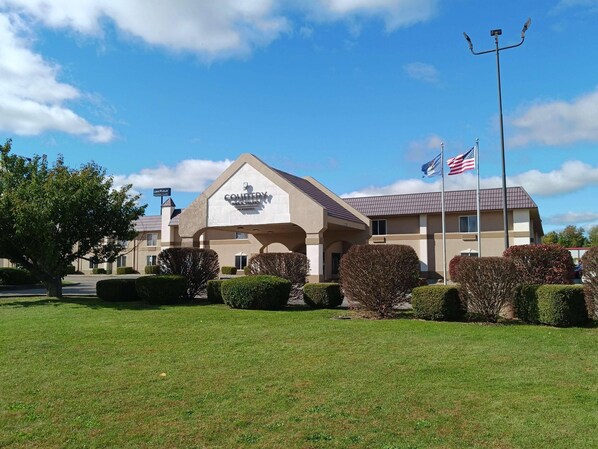 A Courtyard by Marriott hotel with a large sign, American flags, and well-maintained landscaping. - Country Inn & Suites By Radisson, Battle Creek, MI (Battle Creek)