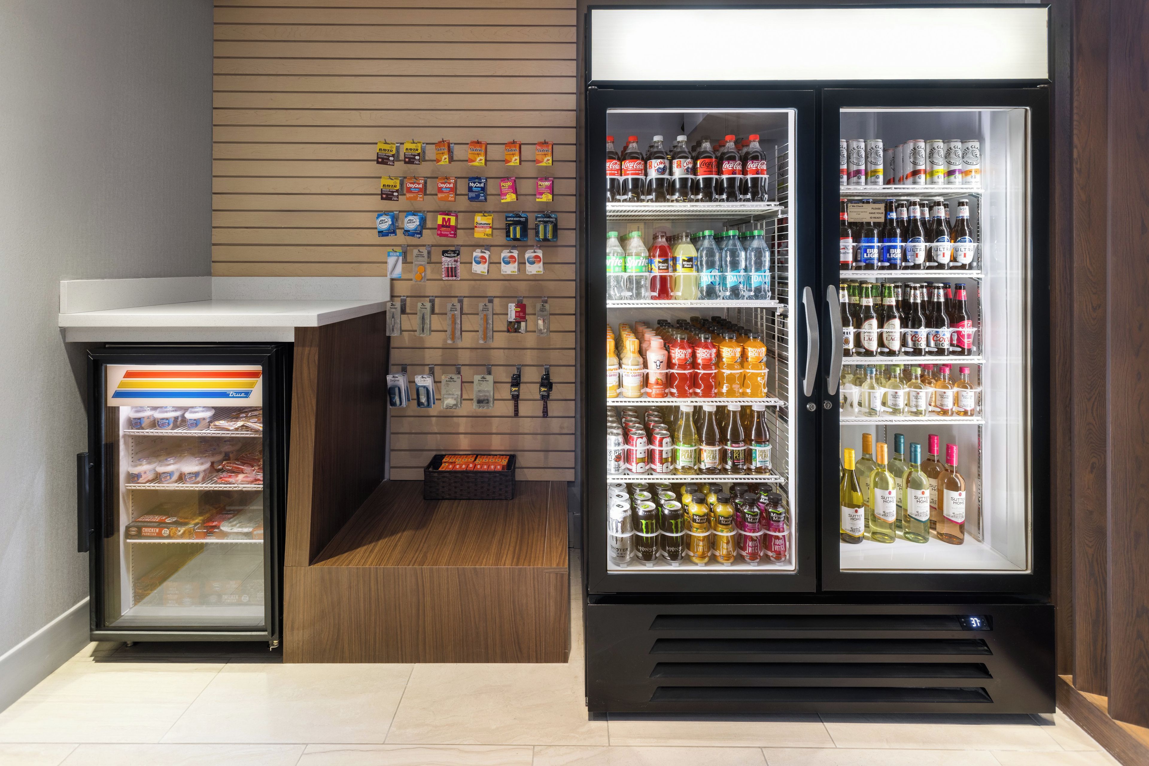 A vending machine with various beverages and snacks, a refrigerator stocked with drinks, and a display of packaged goods on the wall.