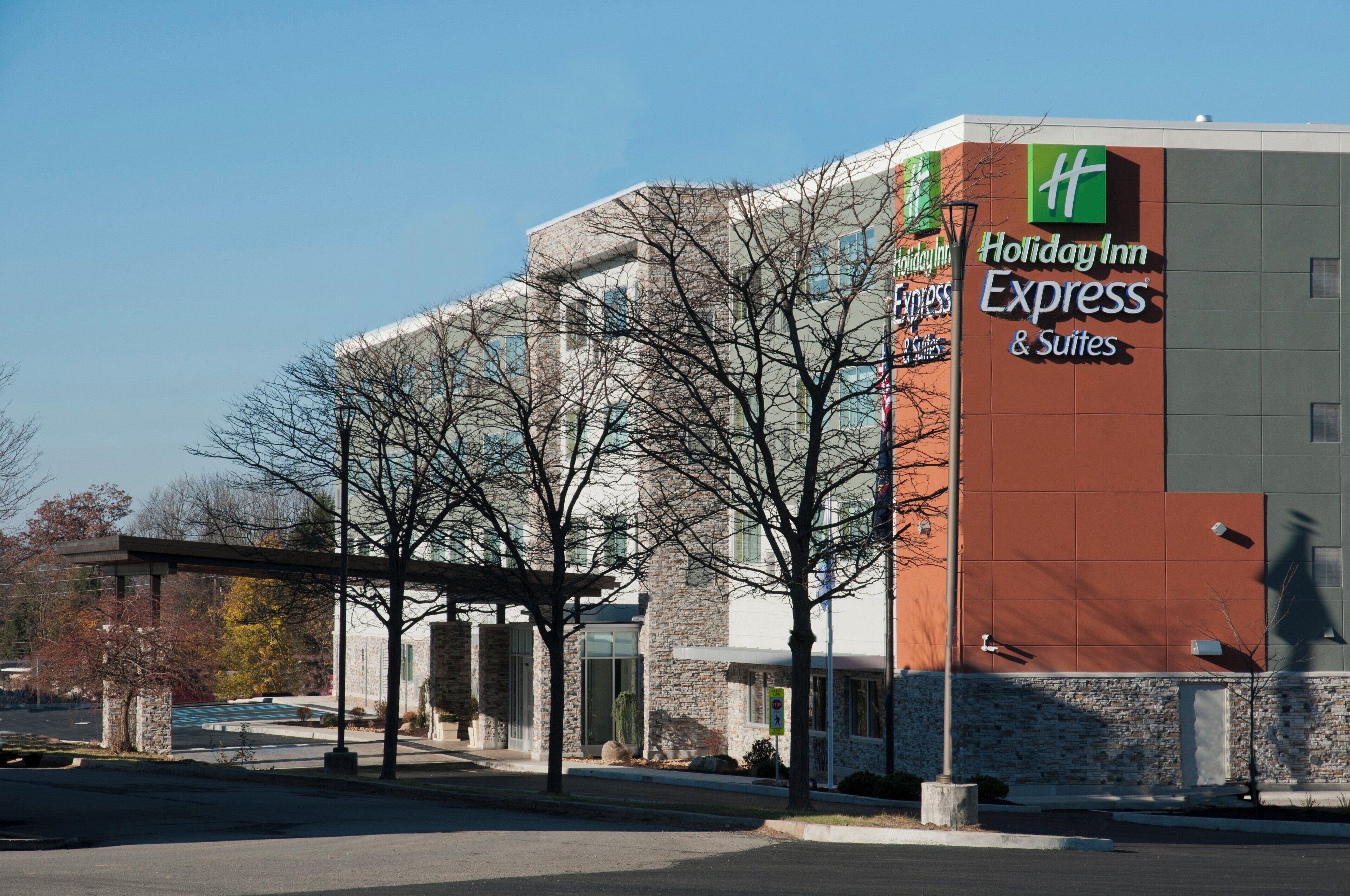 Un bâtiment de la chaîne Holiday Inn Express & Suites, avec une façade en pierre et un ciel d’un bleu éclatant.