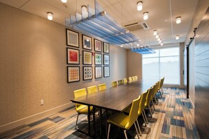 Un salón de conferencias con una larga mesa, sillas amarillas y obras de arte enmarcadas en la pared.