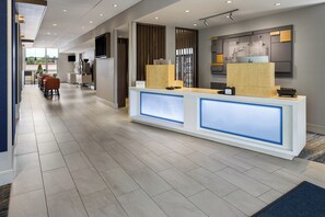 A hotel reception area with a modern design, featuring a reception desk, a seating area, and a view of the outdoor space. - Holiday Inn Express & Suites Johnstown by IHG (Johnstown)