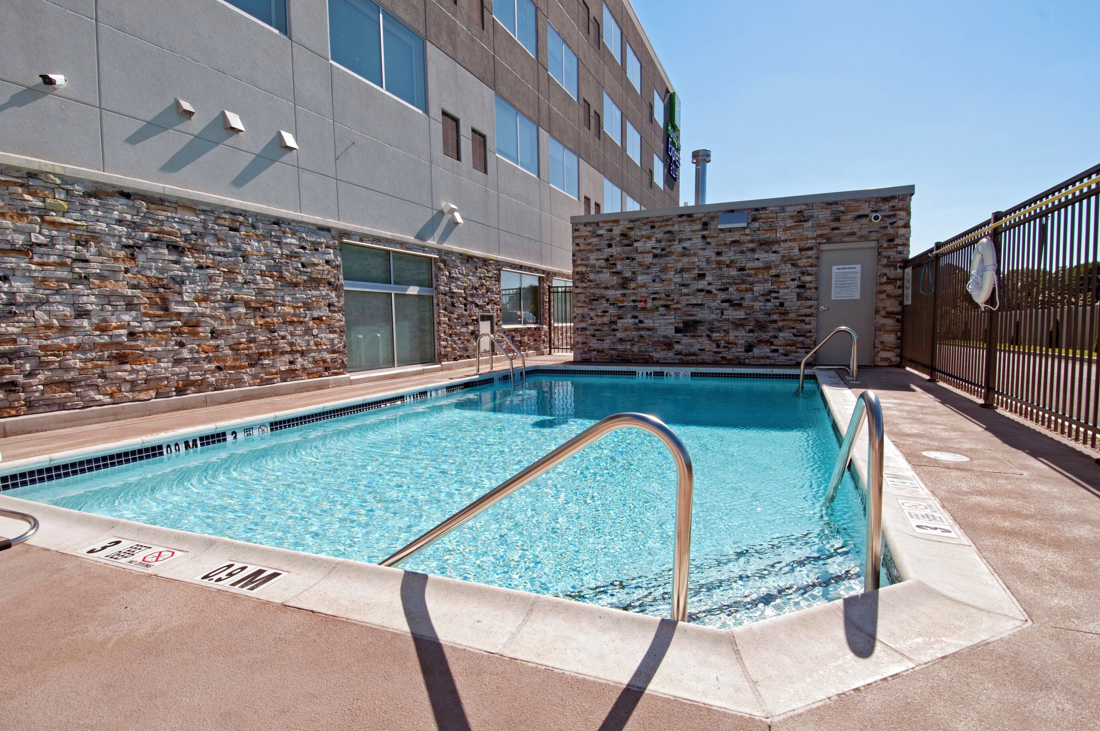 Una piscina con un muro de piedra y una valla metálica.