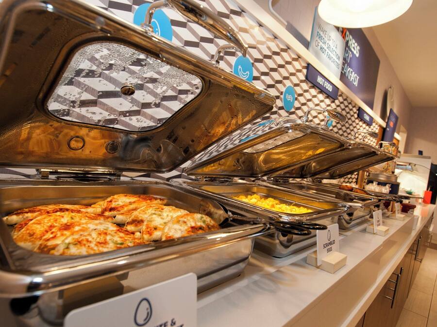 A buffet with various food options, including scrambled eggs and a pizza dish.