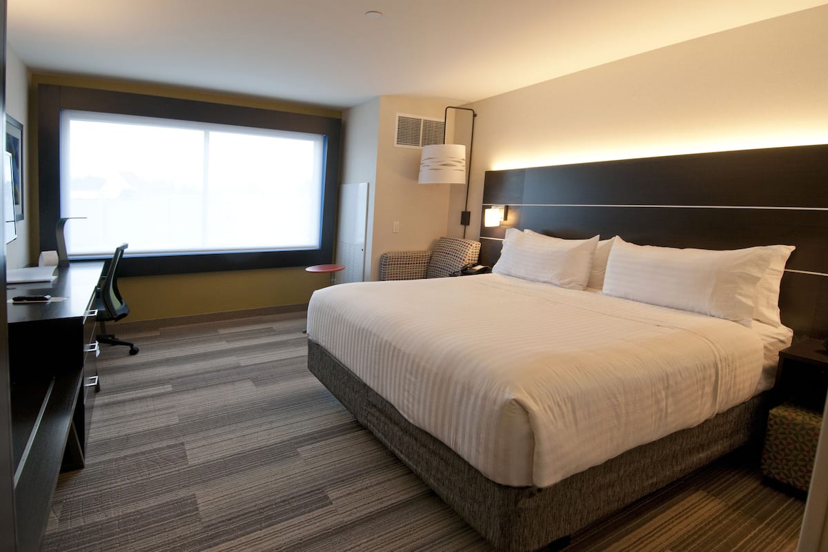 Una habitación de hotel con una cama grande, un escritorio y una silla.