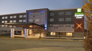 A Holiday Inn Express & Suites building with a stone facade, multiple windows, and a covered entrance area.